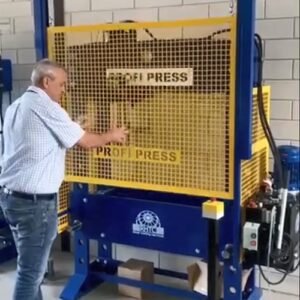 100-ton workshop press with wire mesh front guard, demonstrated by a man.